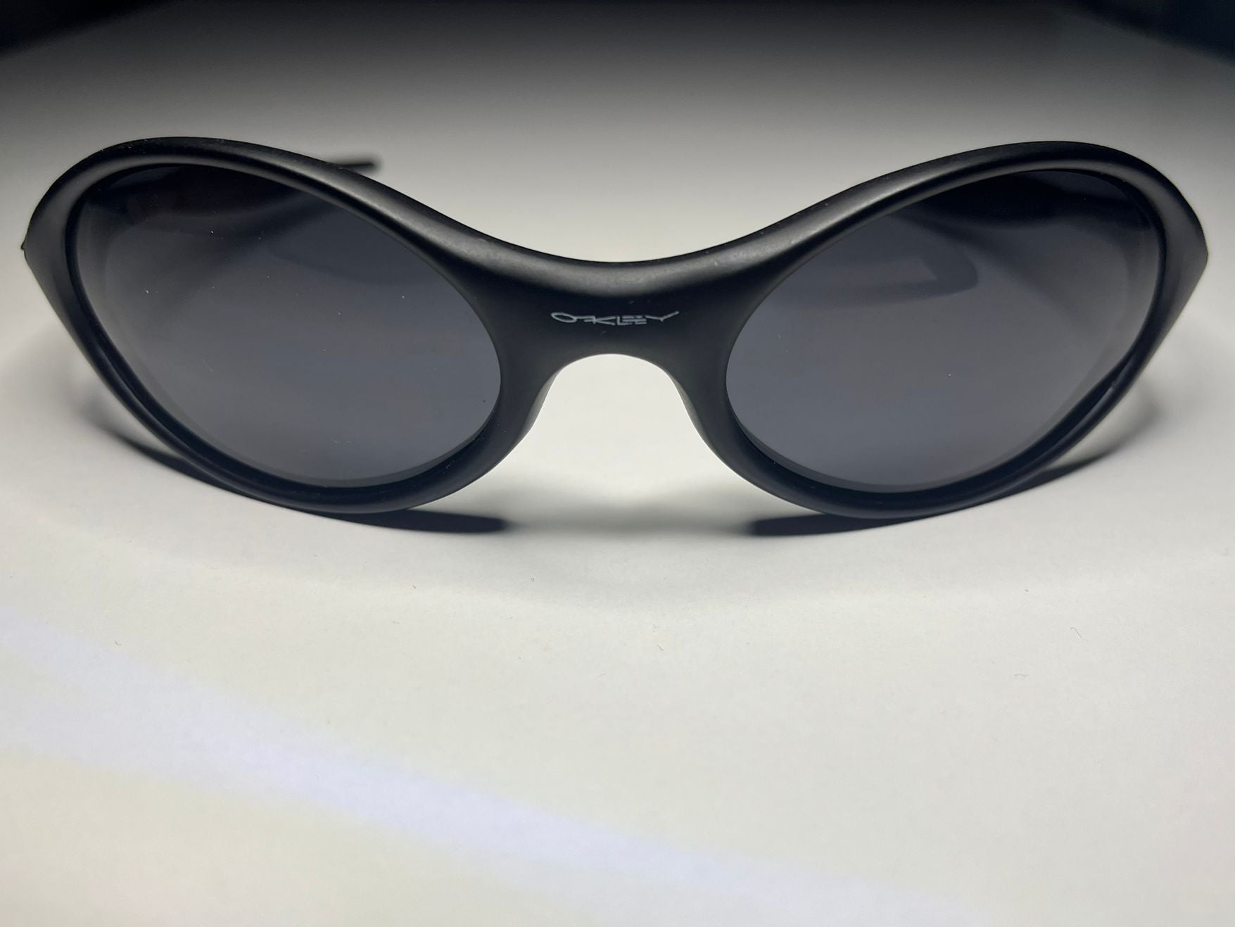 Black sunglasses with dark lenses on a light gray background