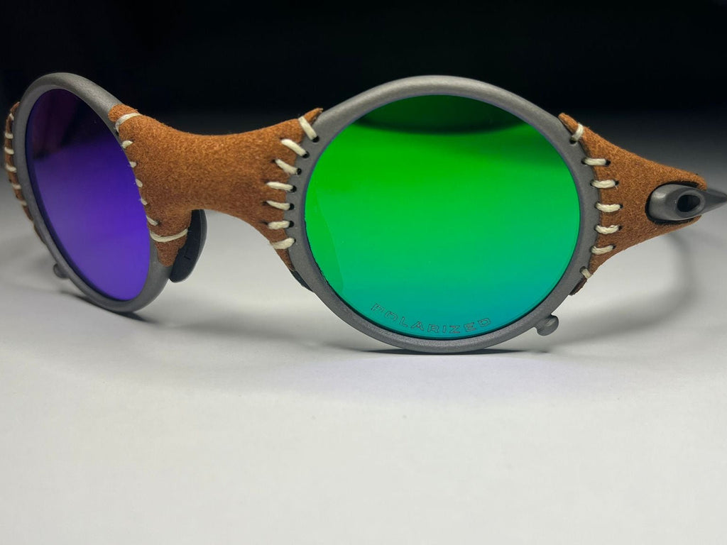 Sunglasses with brown leather frame and green and purple lenses on a white background