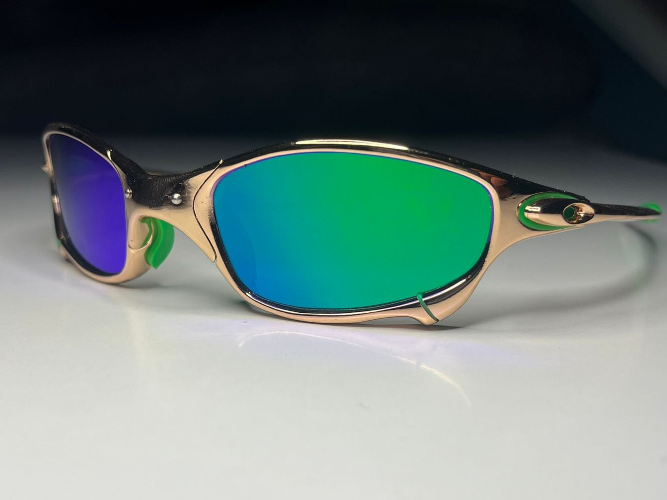 Sunglasses with green lenses and gold frame on a white surface