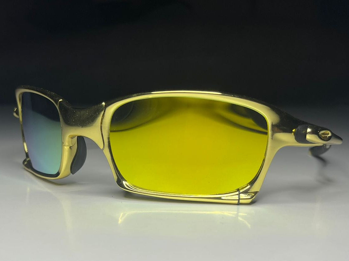 Gold-framed sunglasses with yellow-tinted lenses on a reflective surface.