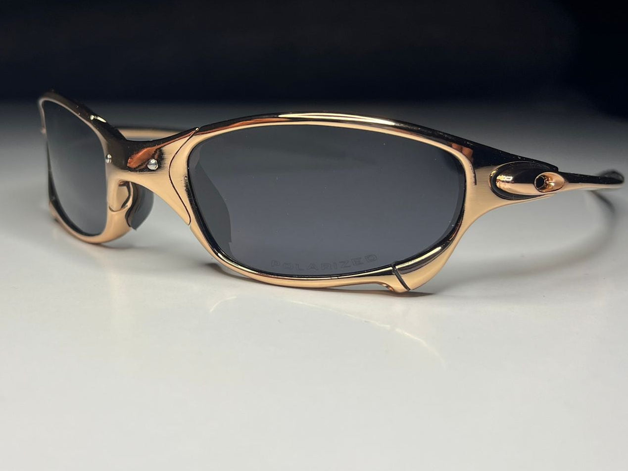 Sunglasses with gold frame and dark lenses on a light surface with dark background