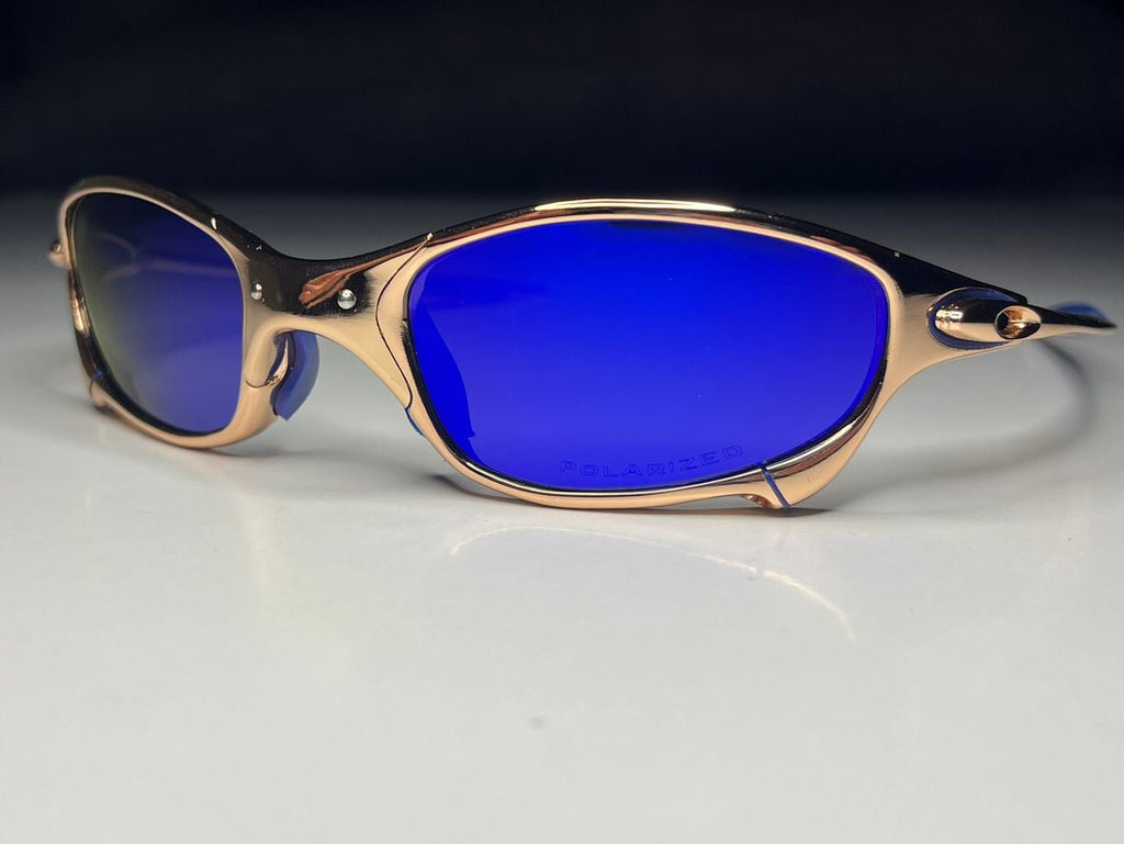 Sunglasses with blue lenses and gold frame on a white surface