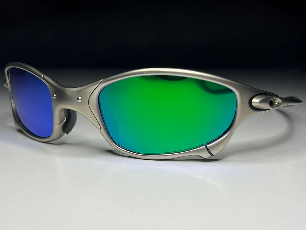 Sunglasses with blue and green lenses on a white surface with black background