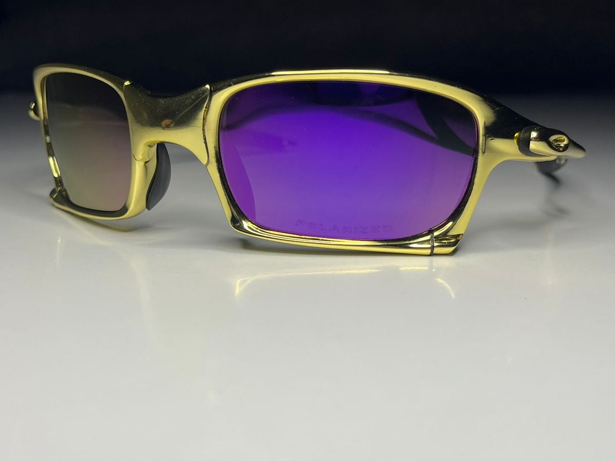 Gold-framed sunglasses with purple lenses on a white surface