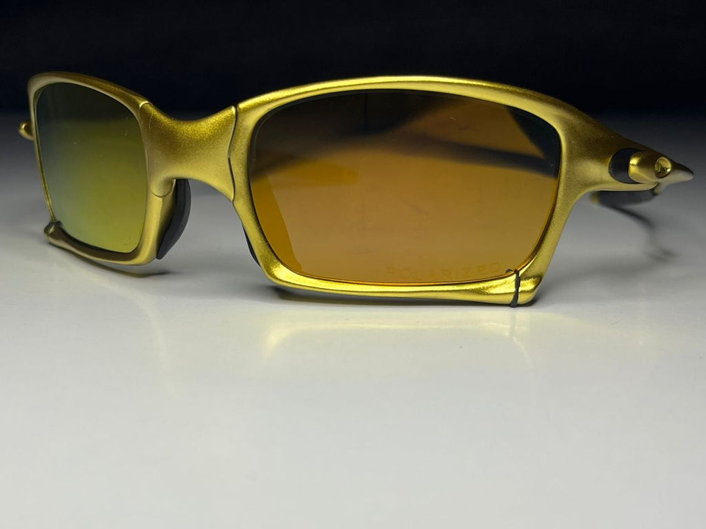 Gold-framed sunglasses with yellow-tinted lenses on a white surface.