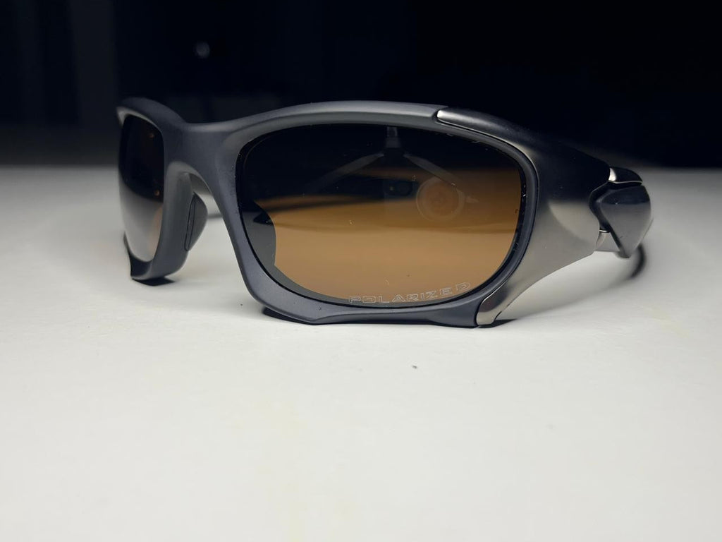 Sunglasses with dark frame and brown lenses on a white surface with black background