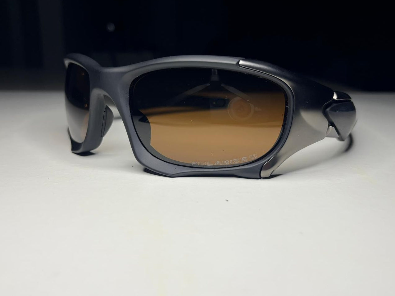 Sunglasses with dark frame and brown lenses on a white surface with black background