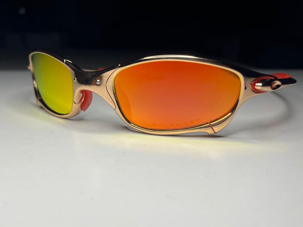 Sunglasses with gold frame and red lenses on a white background